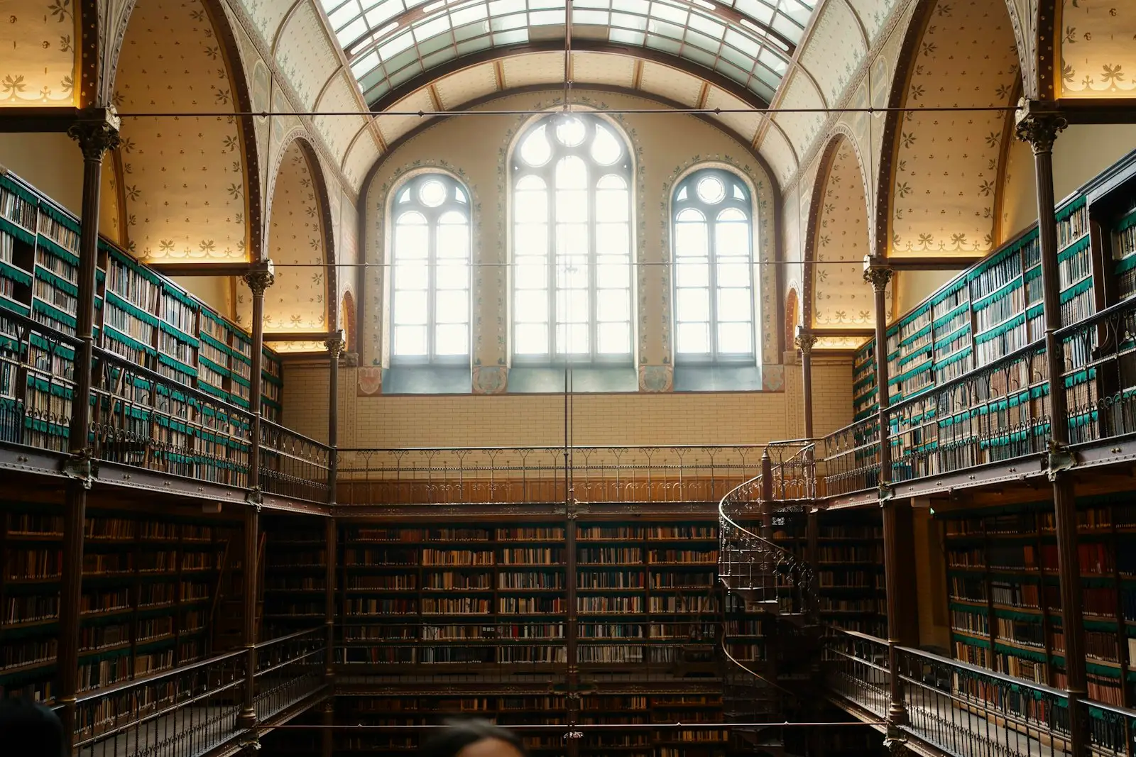 A reading room lined with bookshelves under tall arched windows